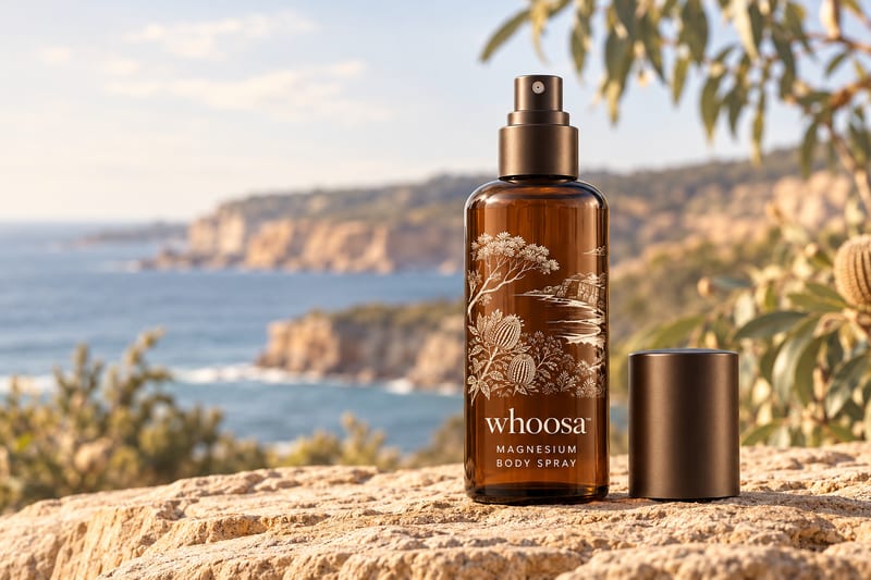 Concept render of the WHOOSA Magnesium Body Spray in amber glass on sandstone, shown for the Three Coasts Spray Trio